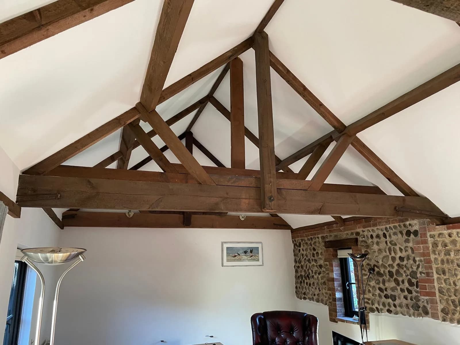 Barn conversion with exposed oak beams and a painted vaulted ceiling
