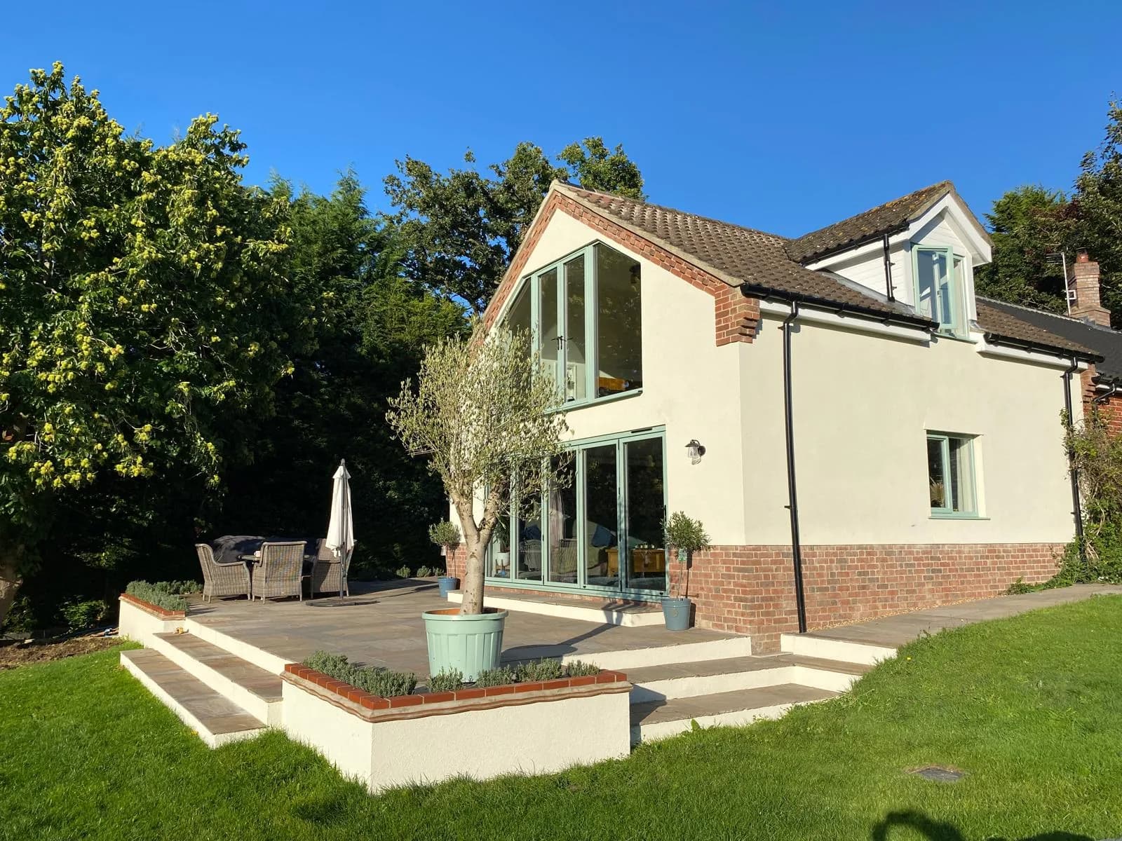 Freshly rendered cottage exterior with sage-green bifold doors
